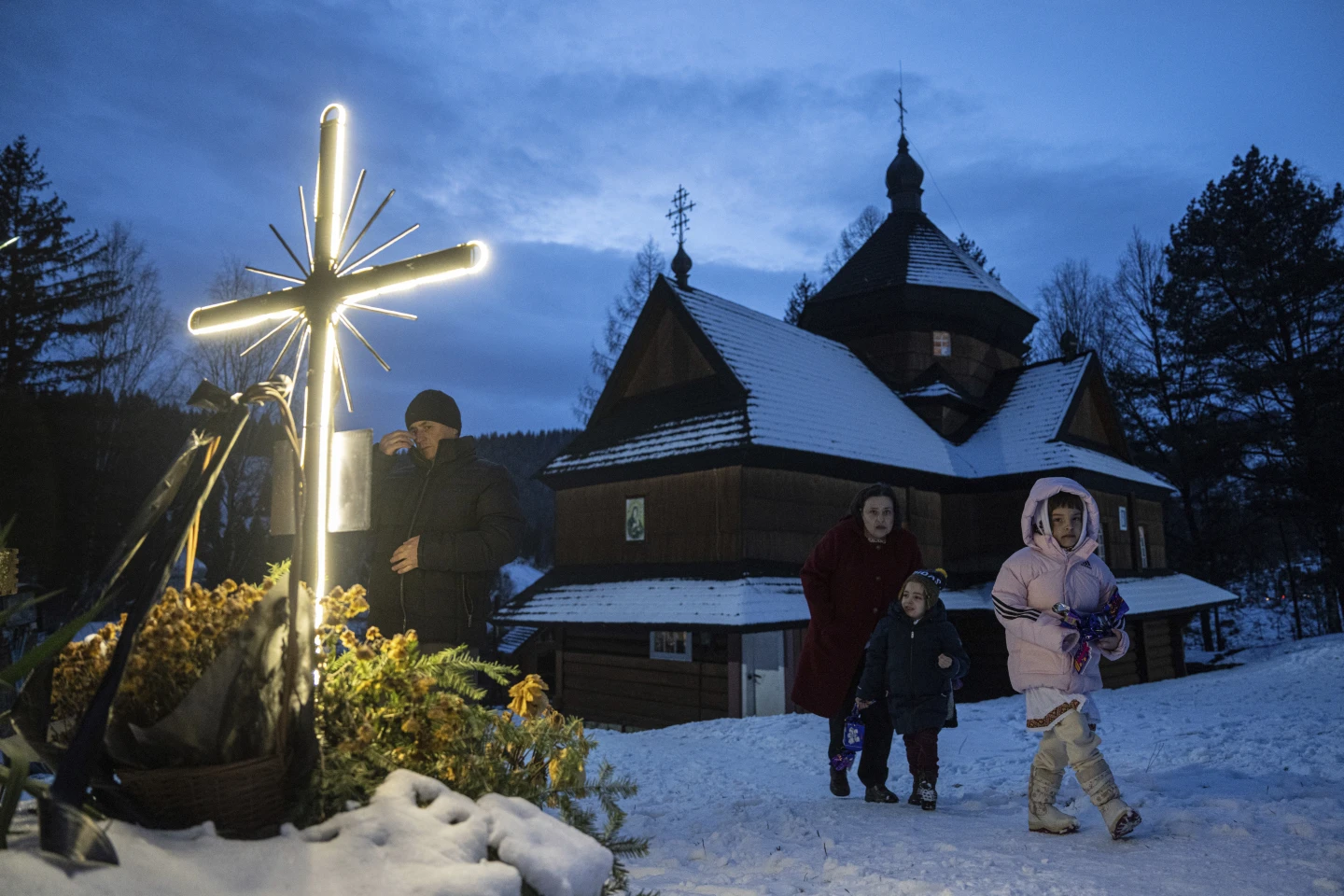 Жінка з дітьми гуляє після церковної різдвяної служби в селі Криворівня, Україна, неділя, 24 грудня 2023 року